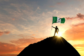 Nigeria flag being waved at the top of a mountain summit. 3D Rendering - obrazy, fototapety, plakaty