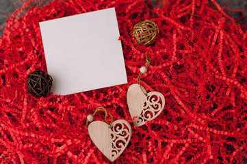 Holiday background for Valentine's Day on a gray cement background with red chopped wrapping paper and hearts.