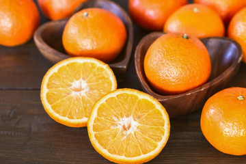 fresh whole tangerines and halves of tangerines in wooden bowls close-up. background with halves and whole tangerines.