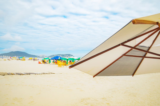 View of a sunshade on foreground and the beach on unfocused on background. Photo taken at Enseada beach, Guaruja SP Brazil. Brazilian tourist destination.
