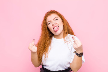 young red head woman feeling provocative, aggressive and obscene, flipping the middle finger, with...