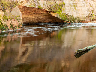 a landscape with a steep river and caves on a sandstone cliff