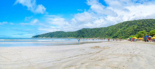 People at a Brazilian beach on a sunny day. Panoramic view. Beach with a calm sea and few waves at...