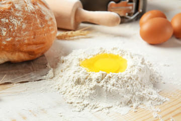 Heap of flour and raw egg on table