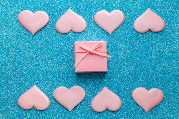 Valentines day pattern background flat lay pink hearts and a pink gift box with rose ribbon on a glittering classic blue background with copy space. love wedding romantic concept, minimal top view