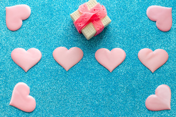Fototapeta premium Valentines day pattern background flat lay pink hearts and a gold gift box with rose ribbon on a glittering classic blue background with copy space. love wedding romantic concept, minimal top view