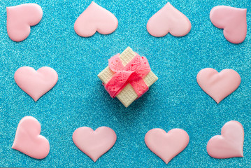 Fototapeta premium Valentines day pattern background flat lay pink hearts and a gold gift box with rose ribbon on a glittering classic blue background with copy space. love wedding romantic concept, minimal top view