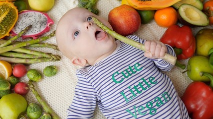 Fototapeta na wymiar Cute Little Vegan Baby Eating Organic Fresh Asparagus Vegetable.