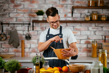 Attractive man cooking in modern kitchen. Handsome chef preparing food.