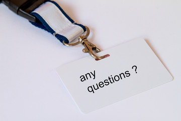 The words any question on a white name tag on a tape