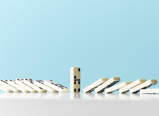 Dominos falling around standing domino against blue background