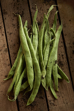 Still life close up fresh, organic, healthy, rustic, dirty green bean pods on wood