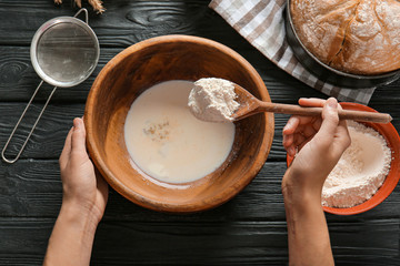 Woman preparing dough in bowl, top view