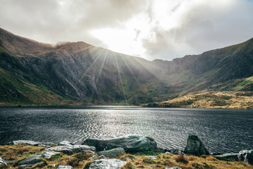 Sun shining over tranquil mountains and lake, Snowdonia NP, UK