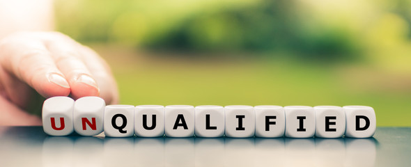 Hand turns dice and changes the word unqualified to qualified.