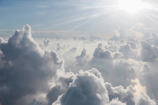 Aerial view sunbeams over fluffy clouds in sky © Martin Barraud/Caia Image
