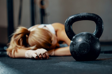 Young exhausted girl lying on a floor of fitness center after training