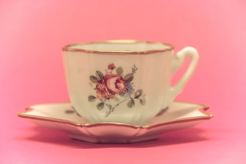 ceramic tea cup with floral paintings on a pink background
