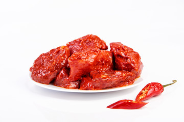 raw meat marinated in spicy sauce close-up, isolated on white background with slices pepper