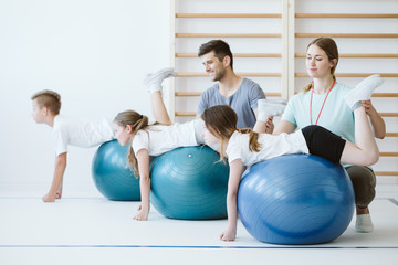 Cute group of kids exercising with balls during sport lesson at school