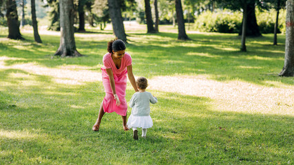 Fototapeta na wymiar Young mother playing in the park with her little daughter