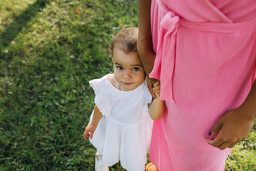 Portrait of a cute little girl standing with mother in the park