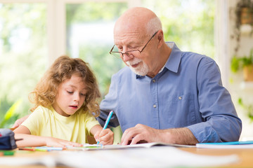 Grey grandfather and his cute grandson do homework