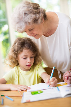 Grey grandmother and her cute grandson do homework