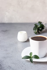 Coffee cup, coffee beans and milk jug on grey stone background. Copy space for text.