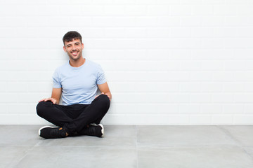 young handsome man looking happy and friendly, smiling and winking an eye at you with a positive...