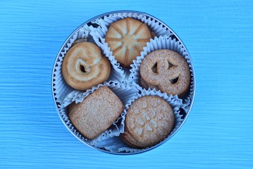 one brown metal box with a set of brown cookies in a white paper package stands on a blue table