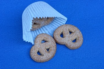 white paper packaging and sprinkled brown cookies with sugar lies on a blue table