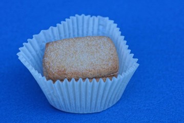 dessert of dry brown cookies in sugar in white paper packaging on a blue table