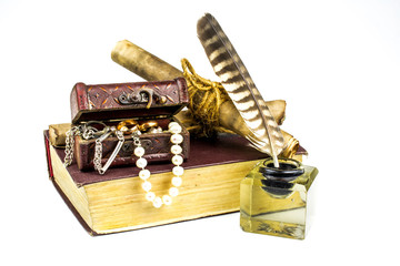 Inkwell with feather, old book, a  chest with jewels  isolated on a  white background.