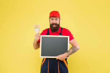 Advertisement concept. bearded worker painting brush. brutal builder man start own business. announcement and advertisement. copy space. professional repairer wanted. builder man paint on blackboard