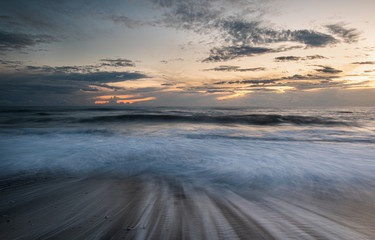 Fototapeta na wymiar Seawaves splashing on the coast during a dramatic sunset