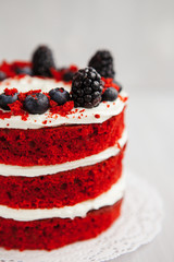  homemade red velvet cake decorated with berries on a light wooden background. valentine's day dessert