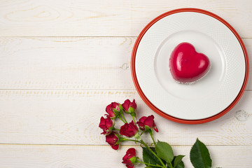 Fototapeta na wymiar Dessert mousse in the shape of a pink glazed heart with a rose, for Valentine's Day. Flat lay