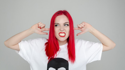 Girl with red hair on a white background. Emotion irritation and anger