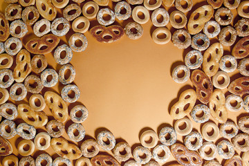 Bublik cookies pattern with copy space, top view. Ring shaped roll cookies with different glaze on orange background..