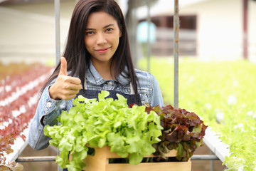 The woman who owns the vegetable garden is carrying fresh vegetables and thumbs up.