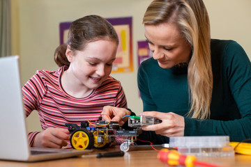 Fototapeta premium Teacher Helping Female Pupil To Build Robot Car In Science Lesson