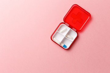 Dose pill box with medical pills on pink background. Top view. Flat lay. Copy space. Pharmaceutical medicine pills, tablets and capsules. Medicine concepts. Trendy pastel color