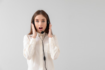 Shocked female technical support agent on light background