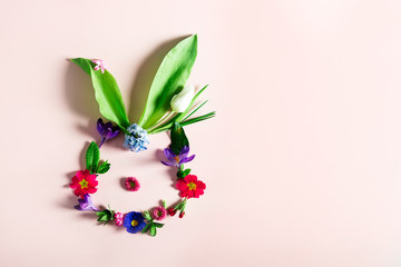 Easter minimal concept. Bunny shape made from spring flowers on the pink background