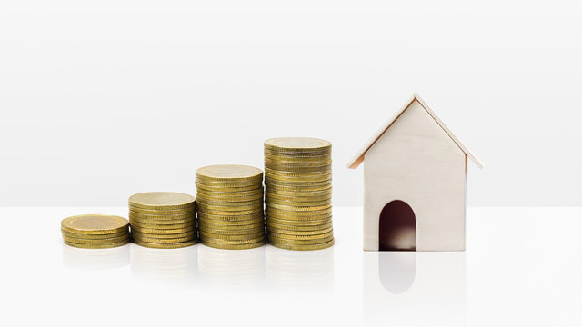 Property investment concept. Home loan mortgage. Financial concept. Growing stack of coins with small house model on white background.