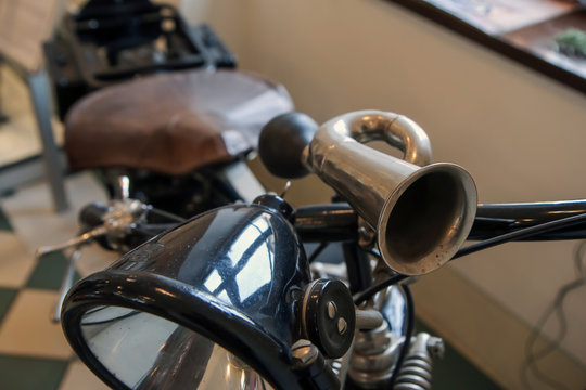 The detail of the old motorcycle with part of the frame, front light, handles and horn. 
