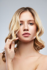 Gorgeous caucasian blond woman with makeup posing in studio and looking at camera.