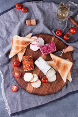 Toasts with tomatoes, goat cheese and basil on a wooden table with a glass of wine.