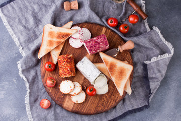 Toasts with tomatoes, goat cheese and basil on a wooden table with a glass of wine.